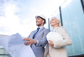 Image showing smiling businessmen with blueprint and helmets