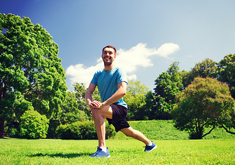 Image showing smiling man stretching outdoors