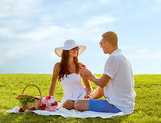 Image showing smiling couple with small red gift box on picnic