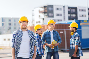 Image showing group of smiling builders in hardhats outdoors