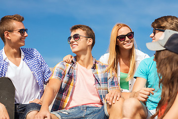 Image showing group of smiling friends sitting on city street