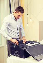 Image showing businessman packing things in suitcase