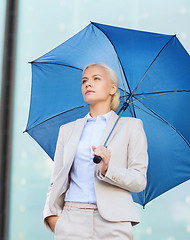 Image showing young serious businesswoman with umbrella outdoors