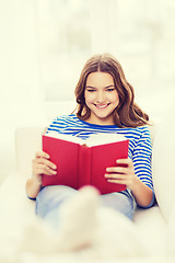 Image showing smiling teenage girl reading book on couch