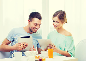 Image showing smiling couple with tablet pc reading news