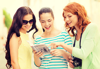 Image showing smiling teenage girls with city guide and camera