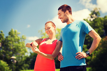 Image showing smiling people with heart rate watches outdoors