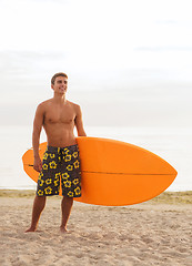 Image showing smiling young man with surfboard on beach