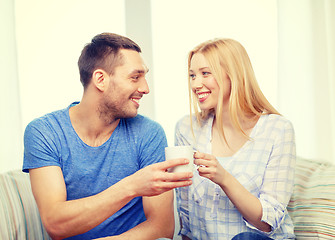 Image showing smiling man giving cup of tea or coffee to wife