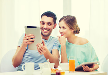 Image showing smiling couple with tablet pc reading news