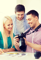 Image showing smiling team with photocamera working in office