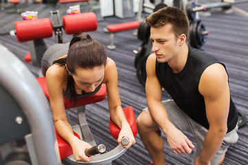 Image showing young woman with trainer exercising on gym machine