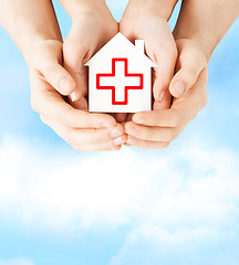 Image showing hands holding paper house with red cross