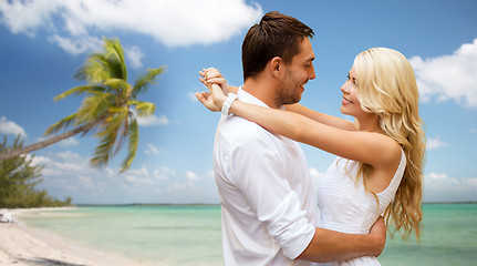 Image showing happy couple hugging over beach background