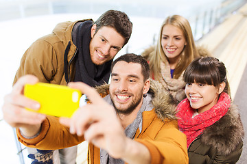 Image showing happy friends with smartphone on skating rink