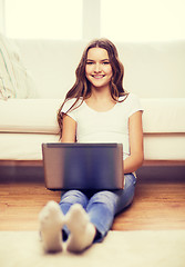 Image showing smiling teenage girl with laptop computer at home