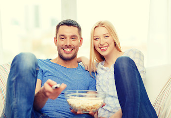 Image showing smiling couple with popcorn watching movie at home