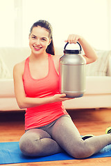 Image showing smiling teenage girl with jar of protein at home