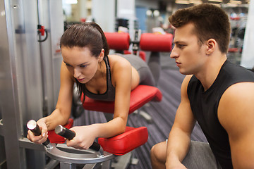 Image showing young woman with trainer exercising on gym machine