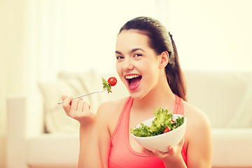 Image showing smiling teenage girl with green salad at home