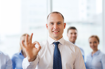 Image showing smiling businessman showing ok sign in office