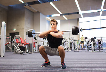 Image showing young man flexing muscles with barbell in gym