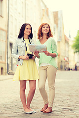 Image showing smiling teenage girls with map and camera