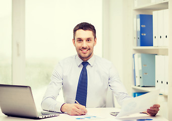 Image showing smiling businessman with laptop and documents