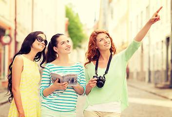 Image showing smiling teenage girls with city guide and camera