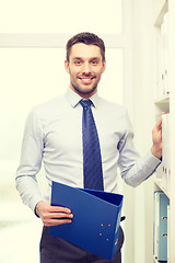 Image showing handsome businessman picking folder at office