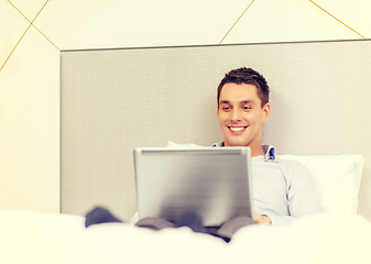 Image showing happy businesswoman with laptop in hotel room