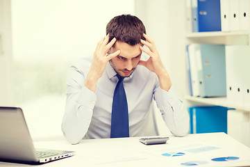 Image showing stressed businessman with laptop and documents