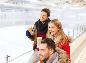 Image showing happy friends with coffee cups on skating rink