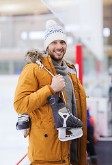 Image showing happy young man with ice-skates on skating rink