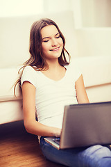 Image showing smiling teenage girl with laptop computer at home