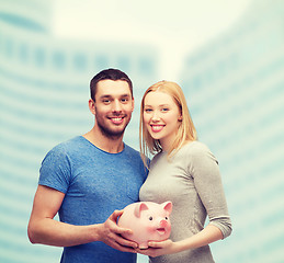 Image showing smiling couple holding big piggy bank