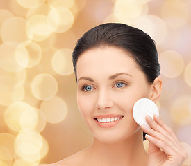 Image showing smiling woman cleaning face skin with cotton pad