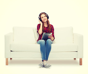 Image showing girl sitting on sofa with headphones and tablet pc