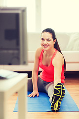 Image showing smiling teenage girl streching on floor at home