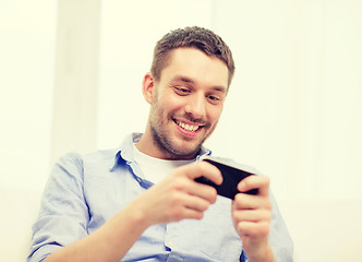 Image showing smiling man with smartphone at home