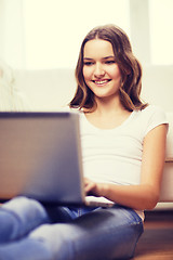 Image showing smiling teenage girl with laptop computer at home