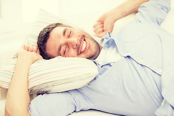 Image showing smiling young man lying on sofa at home