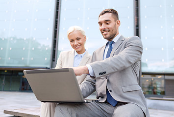 Image showing smiling businesspeople with laptop outdoors