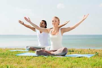 Image showing smiling couple making yoga exercises outdoors