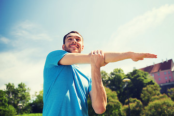 Image showing smiling man stretching outdoors