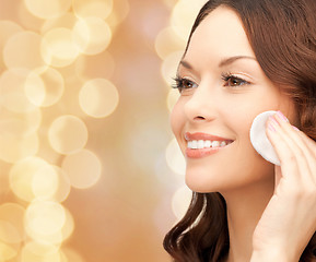 Image showing smiling woman cleaning face skin with cotton pad