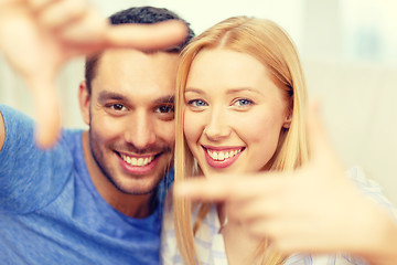 Image showing smiling happy couple making frame gesture at home