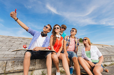 Image showing group of smiling friends with smartphone outdoors