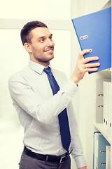 Image showing handsome businessman picking folder at office