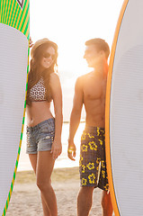 Image showing smiling couple in sunglasses with surfs on beach